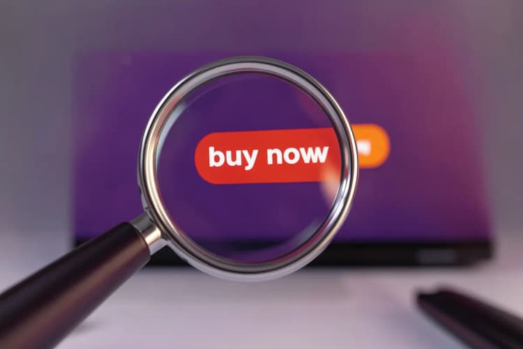 Uma lupa focando em um botão de "comprar agora" em uma tela de computador.