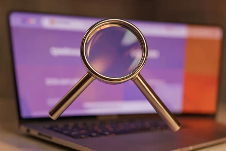 Uma lupa examinando um site em um laptop, simbolizando a análise de problemas de presença online.