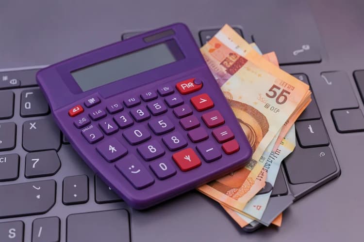 Uma calculadora e notas de dinheiro sobre um teclado de computador.