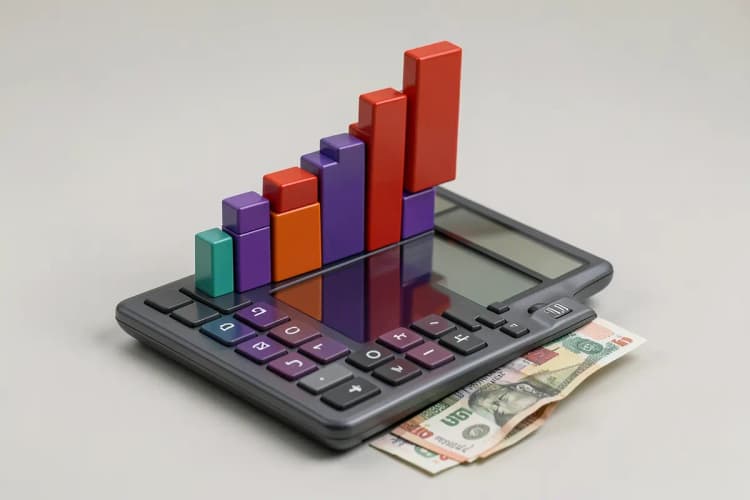 Um gráfico de barras ascendente feito de blocos de construção coloridos, em cima de uma calculadora e algumas notas de dinheiro.