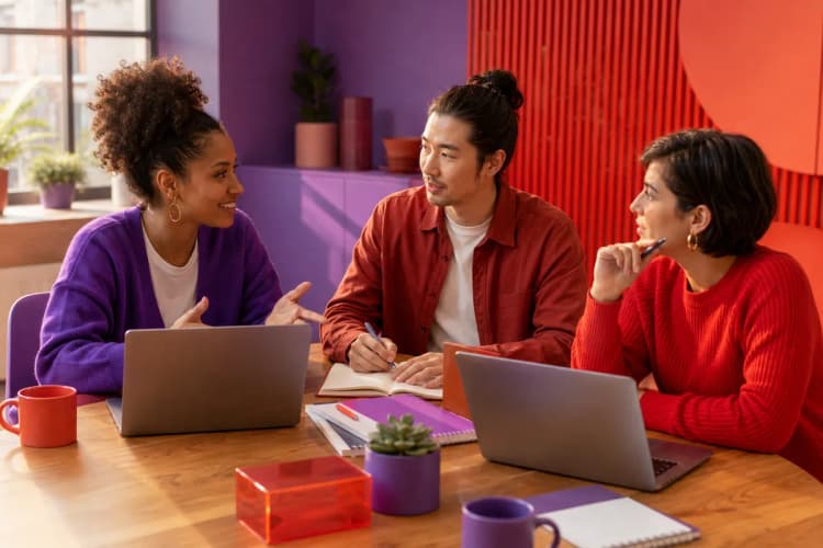 Um grupo diversificado de pequenos empresários em uma reunião, discutindo ideias em torno de uma mesa com laptops e papéis.